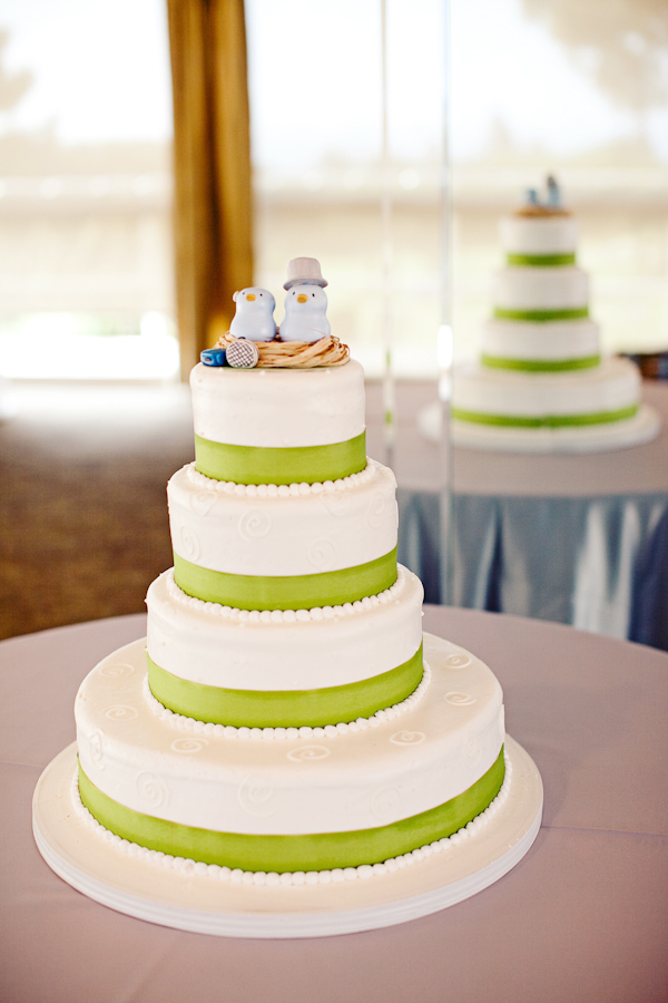 White four tiered cake with light green borders and a lovebirds in a nest topper - photo by San Francisco based wedding photographer Meg Perotti